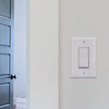 Square crop Electrical rocker light switch on white wall against blurry door background