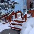 Square crop Oudoor stairs with grate metal treads and green handrails against a building