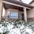 Square crop Snowy evergreens at the yard of brick home with bay window and front porch