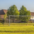 Square crop Soccer goal on vast green grassy field in front of houses viewed on a sunny day Royalty Free Stock Photo