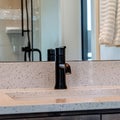Square crop Undermount sink with black faucet on white countertop inside bathroom of home