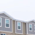 Square crop Upper storey of townhomes with snowy pitched roofs on a cold winter day