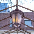 Square crop Vintage outdoor lamp hanging on the gable metal roof frame of a pergola