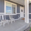 Square crop White porch chairs against window and front door of home with gray exterior wall Royalty Free Stock Photo