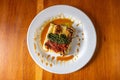 Square of culinary delight artfully displayed on a white plate, set upon a wooden table