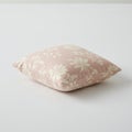 A square decorative pillow with a light pink fabric featuring a white floral pattern. The Royalty Free Stock Photo