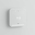 Square digital clock on a light grey wall displays the time \