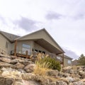 Square Dirt road along homes on a slope with huge rocks and concrete retaining wall