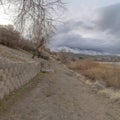 Square Dirt road along the retaining wall of slope overlooking lake and snowy mountain