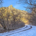 Square Dirt road in snowy Provo Canyon against mountain and blue sky in winter