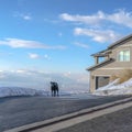 Square Dog on the driveway of a home overlooking Wasatch Mountain and cloudy blue sky Royalty Free Stock Photo