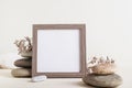 Square empty photo frame near a stack of stones with dried flowers on a light background Royalty Free Stock Photo