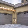 Square Exterior of a home with view of gray double garage doors and stone wall