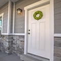 Square Facade of a home with a simple wreath hanging on the white wooden door Royalty Free Stock Photo