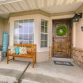 Square Facade of a home with a wooden bench on the welcoming front porch