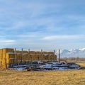 Square Farm in Eagle Mountain Utah with stacks of hay and snowy logs in winter Royalty Free Stock Photo