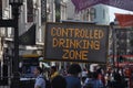 Square filled with people with the sign `Controlled drinking zone`