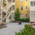 Square Fire pit and stone benches outside a multi storey residential building complex