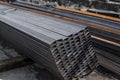 Square flat-rolled pipe metal profile in packs at the warehouse of metal products. Weathered metals profiles for