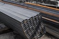 Square flat-rolled pipe metal profile in packs at the warehouse of metal products. Weathered metals profiles for