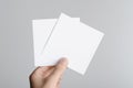 Square Flyer / Invitation Mock-Up - Male hands holding blank flyers on a gray background Royalty Free Stock Photo
