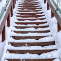 Square Focus on stairway that goes up a snowy hill with residential homes in winter