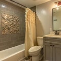 Square frame Bathroom with vanity and toilet against white wall and bathtub against tile wall Royalty Free Stock Photo