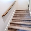 Square frame Carpeted indoor staircase of home with brown handrail against white side wall Royalty Free Stock Photo