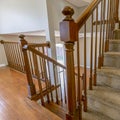 Square frame Carpeted staircase with brown handrail inside a house with shiny wooden floor