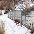 Square frame Chain link fence with barbed wires on snow covered hill slope viewed in winter