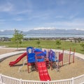 Square frame Childrens playground ovelooking homes lake and snow peaked mountain under sky