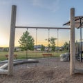 Square frame Childrens playground at a park with swings slides and umbrellas viewed at sunset