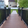 Square frame Close up of bridge with brown wood deck and black guardrail over a grassy pond