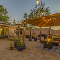 Square frame Cozy stone patio with string of lights over a covered seating and dining area
