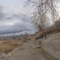 Square frame Dirt road along the retaining wall of slope overlooking lake and snowy mountain