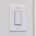 Square frame Electrical rocker light switch with flat broad lever on white interior wall