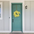 Square frame Exterior of a house with gray walls and blue green door with yellow flower wreath Royalty Free Stock Photo