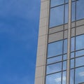 Square frame Focus on a modern building exterior with glass windows reflecting the blue sky Royalty Free Stock Photo