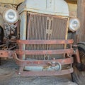 Square frame Front of an old and vintage tractor against stone wall and roof of a farm barn Royalty Free Stock Photo