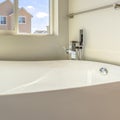 Square frame Glossy bathtub and wall mounted towel rod inside a bathroom lit by sunlight