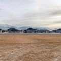 Square frame Grass covered terrain with distant snowy mountain and houses in the background Royalty Free Stock Photo