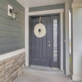 Square frame Gray front door with white holiday wreath and narrow sidelight at home facade Royalty Free Stock Photo