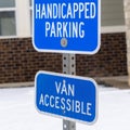 Square frame Handicapped Parking and Van Accessible sign against snow and building in winter Royalty Free Stock Photo