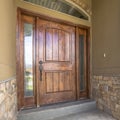 Square frame Home porch and brown wood front door with sidelights and arched transom window