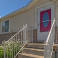 Square frame Home with stairs going uo to the red front door against brick and concrete wall Royalty Free Stock Photo