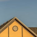 Square frame House exterior with roof shingles and round gable window against blue sky Royalty Free Stock Photo