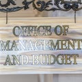 Square frame Office Of Management And Budget sign hanging on decrative wrought iron hanger