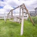 Square frame Old wooden garden swing on lush green grasses inside white picket fence Royalty Free Stock Photo