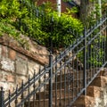 Square frame Outdoor staircase with stone steps and black metal railing against a fence Royalty Free Stock Photo