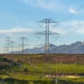 Square frame Power lines towering over neighborhood and roads in the valley on a sunny day Royalty Free Stock Photo